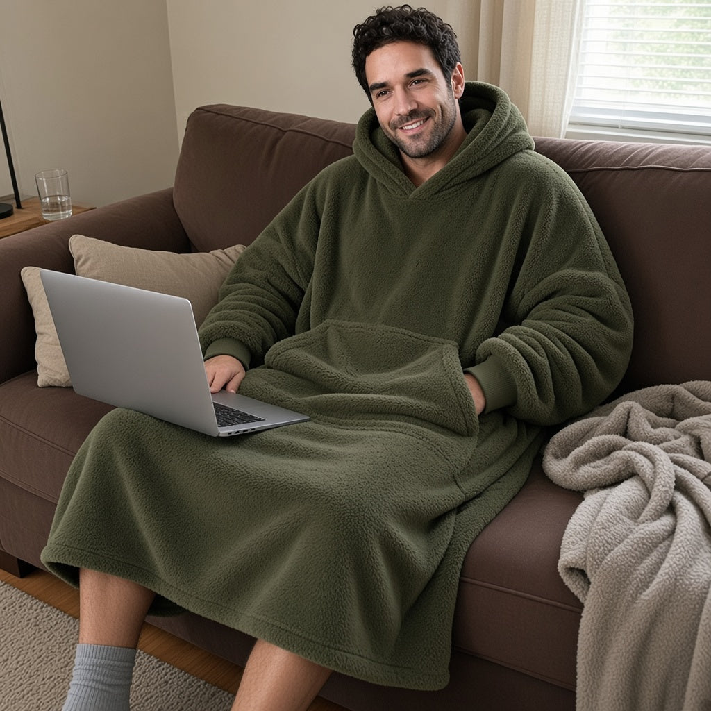 Man relaxing on couch with laptop wearing army green oversized blanket hoodie